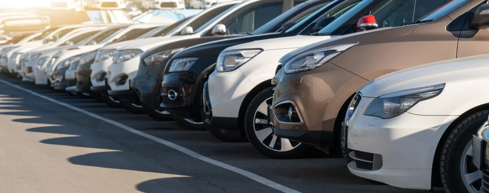 Trois voitures stationnées dans une allée de showroom avec des états différents.